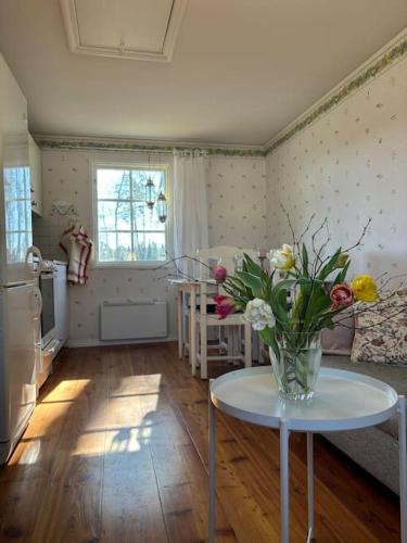 a living room with a vase of flowers on a table at Gästhus i gårdsmiljö in Forsheda