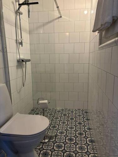 a bathroom with a toilet and a tiled floor at Gästhus i gårdsmiljö in Forsheda
