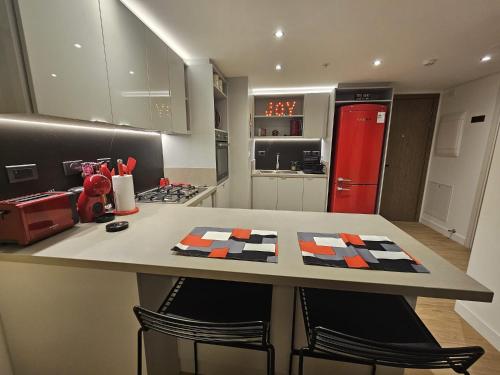 a kitchen with a counter with chairs and a red refrigerator at JOY MONTEVIDEO - Apartamento Premium - Servicios de Hotel 5 Estrellas in Montevideo