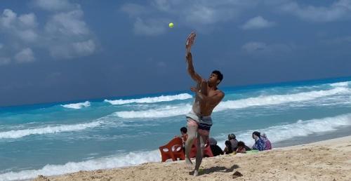 a man hitting a tennis ball on the beach at استوديو للعائلات داخل قرية Retal View north coast in El Alamein