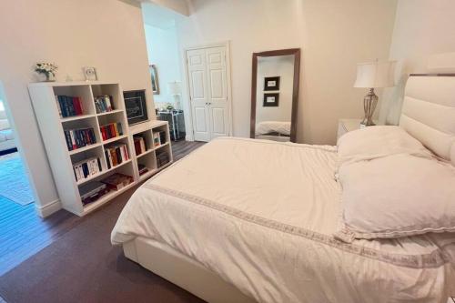 um quarto com uma cama branca e prateleiras de livros em Bluebird Sanctuary - Howe island Luxury Retreat em Pittsburgh