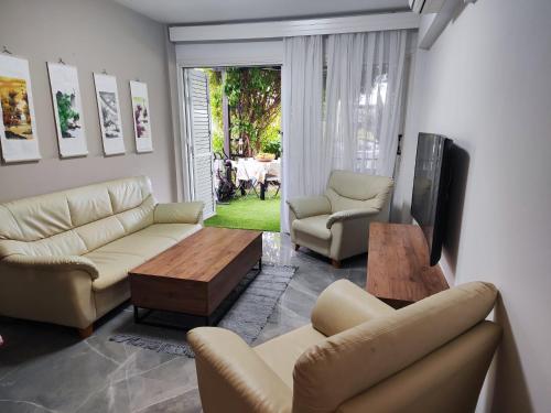 a living room with couches and a table and a tv at Pampering Beach Dream, A Stunning Luxury Retreat at Yialos Village in Meneou
