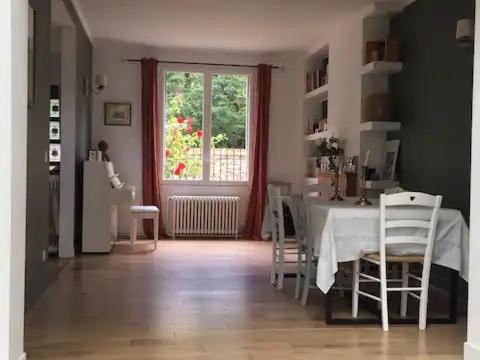 a dining room with a table and chairs and a window at Maison idéalement située à Versailles in Versailles