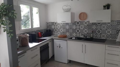 une cuisine avec des armoires blanches et du carrelage noir et blanc dans l'établissement Appartement La Garance, Gites de Daumesnil, à Morlaix
