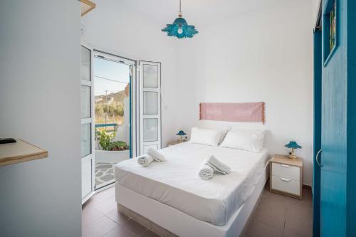 um quarto com uma cama com lençóis brancos e uma janela em Alcyone em Serifos Chora