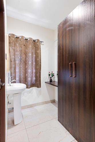 a bathroom with a wooden door and a sink at VEERA RESIDENCY in Tiruvallūr