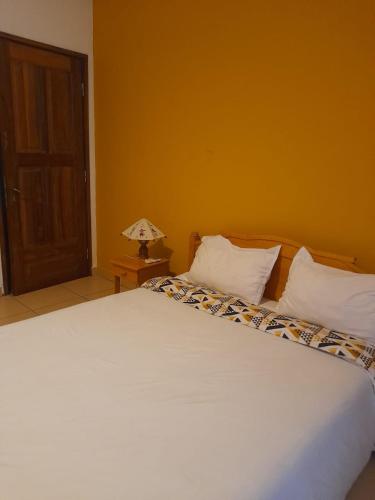 um quarto com uma cama branca e um candeeiro sobre uma mesa em Hôtel les Cygnes II em Antananarivo