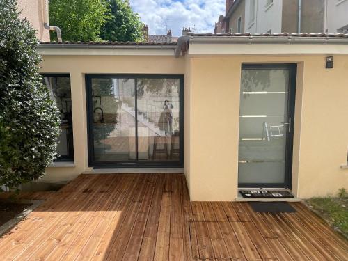 une maison avec des portes coulissantes en verre sur une terrasse en bois dans l'établissement Studio Vichy Marol, à Vichy