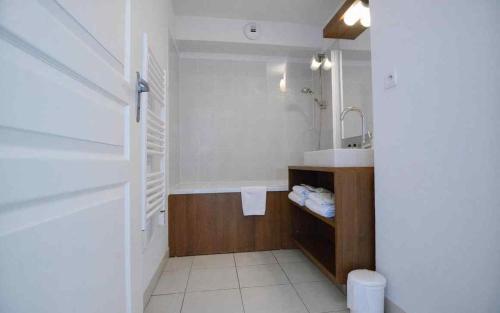 a white bathroom with a sink and a tub at Appartement entier dans résidence de tourisme in Azille