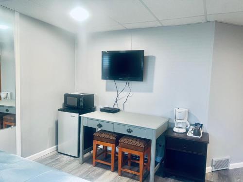 a room with a desk with a tv on the wall at Falls Motel in Niagara Falls