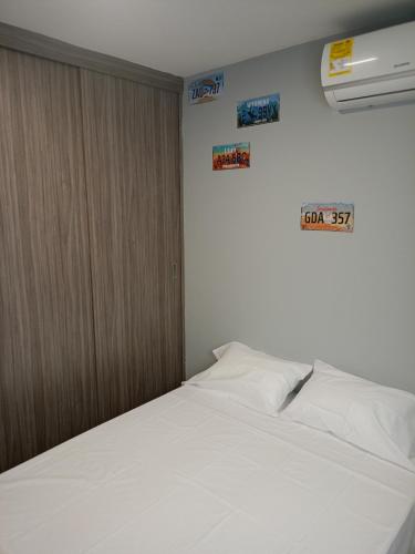 Cama blanca en una habitación con carteles en la pared en Excepcional Apartamento, en Valledupar