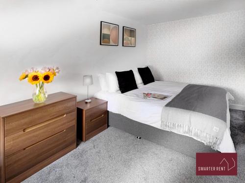 a bedroom with a bed with a vase of flowers on it at Hitchin - St Anne's - 2 bed coach house & Parking in London Colney