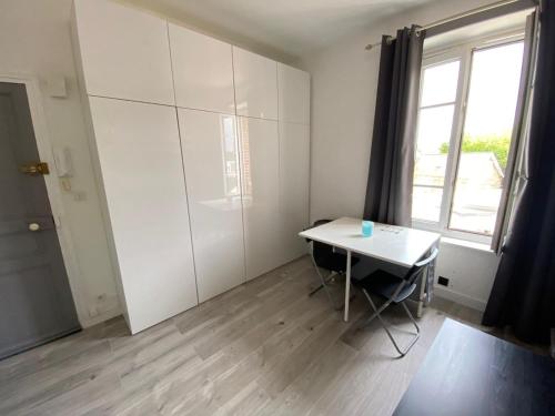 Cette chambre blanche dispose d'une table et d'une fenêtre. dans l'établissement Studio à 100m à pied de la plage et de la digue du sillon, à Saint-Malo