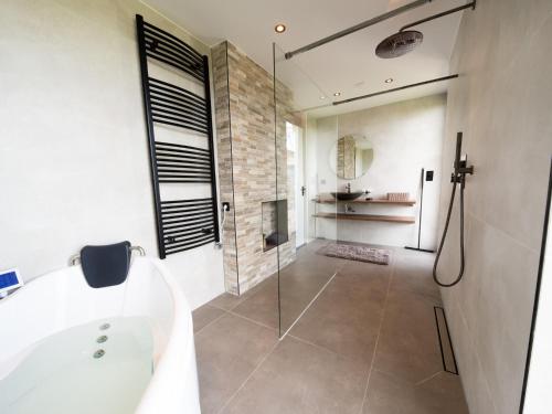 a bathroom with a shower and a tub and a sink at Wellness Bungalow with whirlpool and sauna in Zevenhuizen