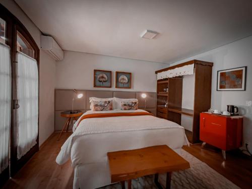 a bedroom with a large bed and a table at Hotel Harmonia Monte Verde in Monte Verde
