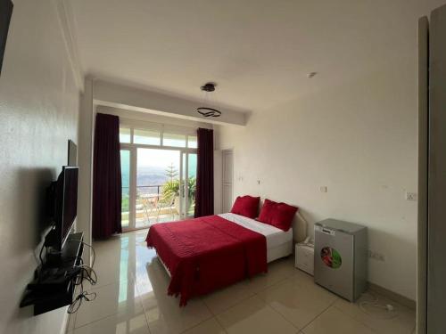 Schlafzimmer mit einem Bett mit roter Bettwäsche und einem Fenster in der Unterkunft NBE Apartment in Kigali
