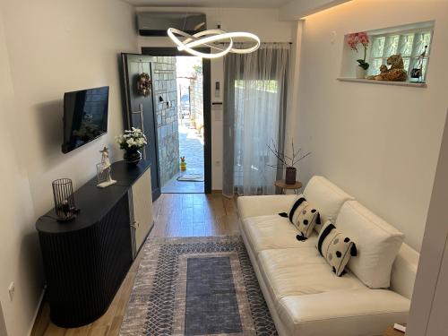 a living room with a white couch and a tv at HOME OF OLYMPOS STUDIO in Litochoro