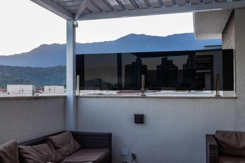 een balkon met een bank en uitzicht op de stad bij Serena Beach Triplex in Caraguatatuba