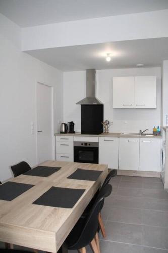 une cuisine avec une table en bois et des armoires blanches dans l'établissement Flik-en-flac - Appartement à 20m de la plage, à Roscoff