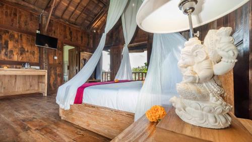 ein Schlafzimmer mit einem Himmelbett mit einer weißen Statue in der Unterkunft Picturesque Private Joglo Villa Near Monkey Forest in Ubud