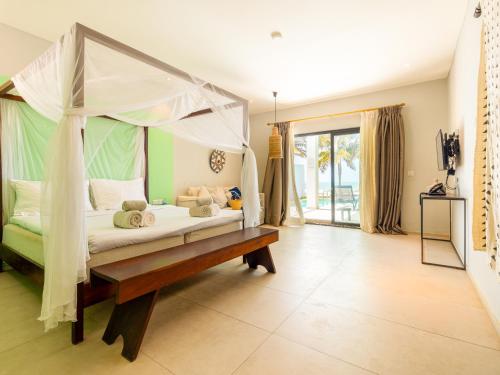 a bedroom with a canopy bed and a wooden bench at Tamala Beach Resort in Kotu