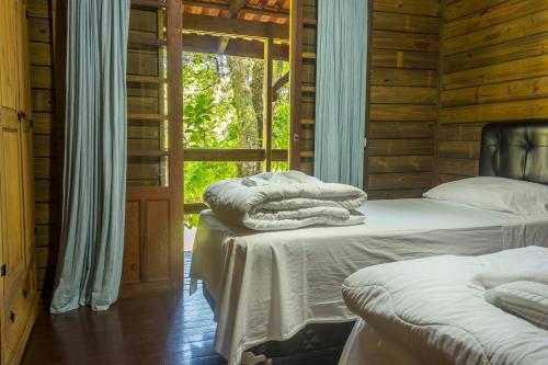 2 camas num quarto de madeira com uma janela em Fazenda dos Caetés em Camboriú