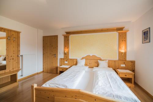 a large bed in a bedroom with wooden furniture at Klaudehof in Dobbiaco