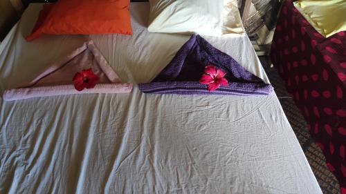a white bed with two pillows with flowers on it at Tanna tree house and bangalows in Lénakel