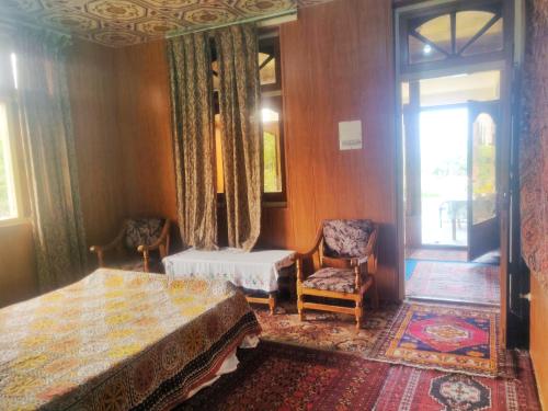 a bedroom with a bed and two chairs and a window at Serene Guest House in Gilgit