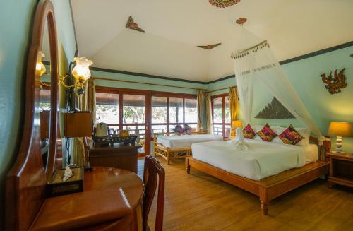 a bedroom with two beds and a table and a desk at Chaweng Buri Resort in Chaweng