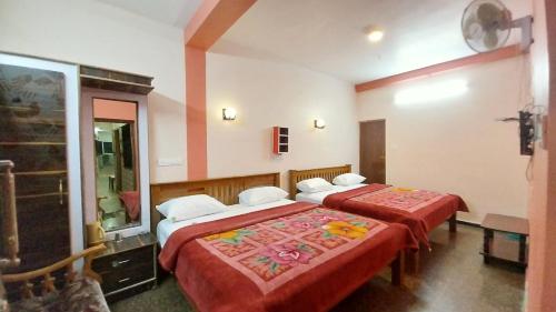 a hotel room with two beds with red sheets at SV RESIDENCY in Ooty