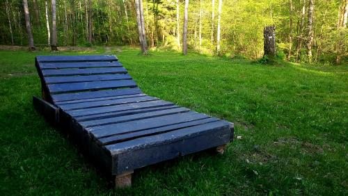 a wooden bench sitting in the grass in a field at EKO Domek u Siemion in Raczki