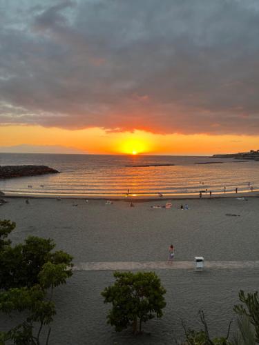 a sunset on a beach with people in the water at Tenerife Paradise Anna Studio in Adeje