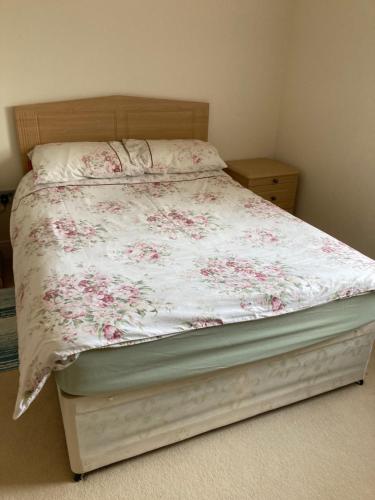 a bed with a floral comforter on it in a bedroom at Private room Bishop Norton 
