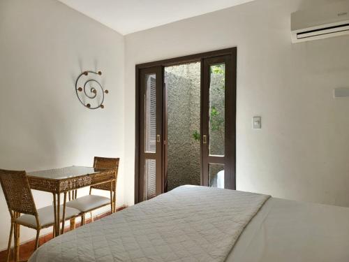 a bedroom with a bed and a table and a window at Pousada Porto Fino in Cabo Frio