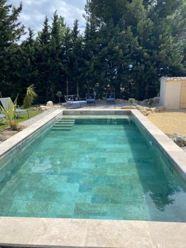 une piscine avec de l'eau bleue dans une cour dans l'établissement Gîtes chez Marceau, à Rasteau
