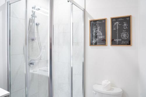 a bathroom with a shower with a toilet and two framed pictures at The Céilí Cottage by Revelstoke Vacations in Revelstoke