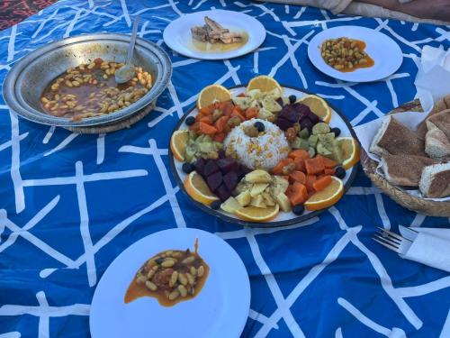 a table with plates of food on a blue table cloth at Sahara Camp Light in Mhamid