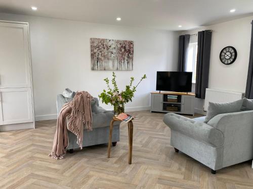 a living room with a couch and a tv at Blossom Lodge - 3 Bedroom Bungalow in Norfolk Perfect for Families and Groups of Friends in Narborough