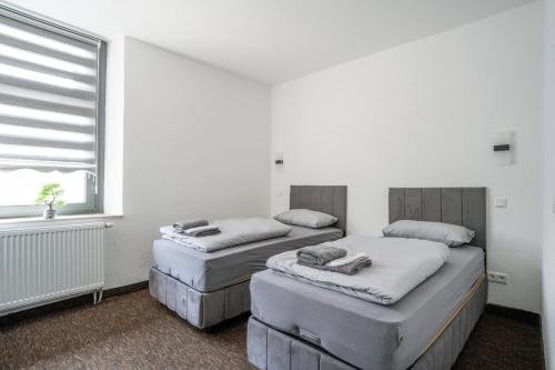 two beds in a white room with a window at Duisburger Hostel in Duisburg