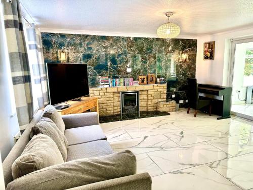 uma sala de estar com um sofá, uma televisão e um piano em Luxury Large Four Bedroom Family Home Free Car Park em Luton