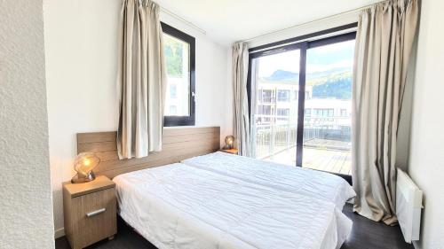 une chambre avec un lit et une grande fenêtre dans l'établissement Résidence Les Terrasses De Veret - Appartement lumineux · Au pied des pistes · Piscine · Parking inclus · Spa MAE-1651, à Magland