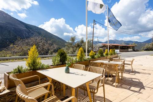 a patio with tables and chairs with mountains in the background at Denthis Hotel - Taygetos Mountain Getaway in Artemisía
