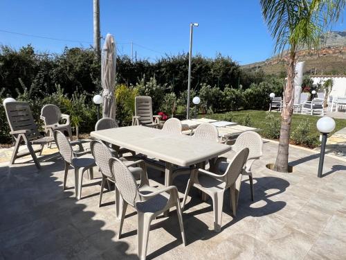 a white table and chairs and a table and a palm tree at Scopello Guidaloca Villas in Scopello