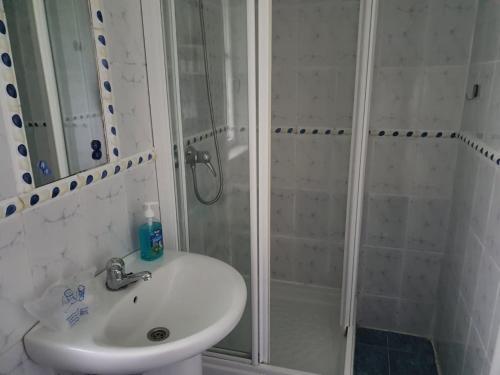 uma casa de banho branca com um chuveiro e um lavatório. em alojamiento con jardin y barbacoa em Cangas de Onís