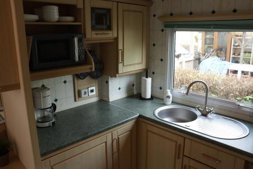 a kitchen counter with a sink and a window at Kom heerlijk tot rust in Casa Debonair in Peperga
