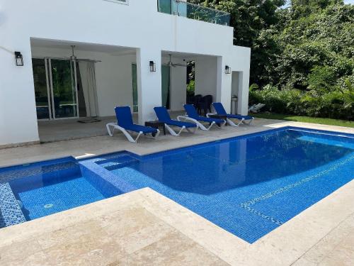 a swimming pool with blue chairs and a house at Family House in La Romana in La Romana