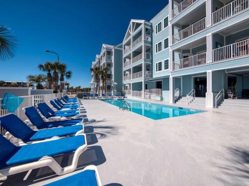 a row of blue lounge chairs next to a building at Grand Caribbean 115 by Vacation Homes Collection in Orange Beach