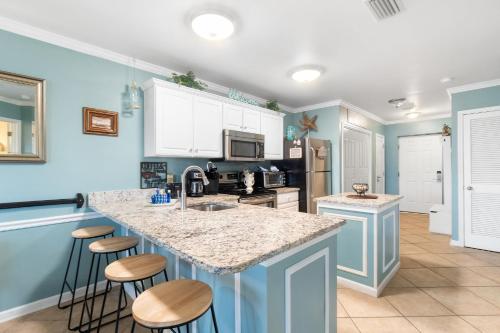 una cocina con paredes azules y una isla con taburetes. en Grand Caribbean 115 by Vacation Homes Collection, en Orange Beach