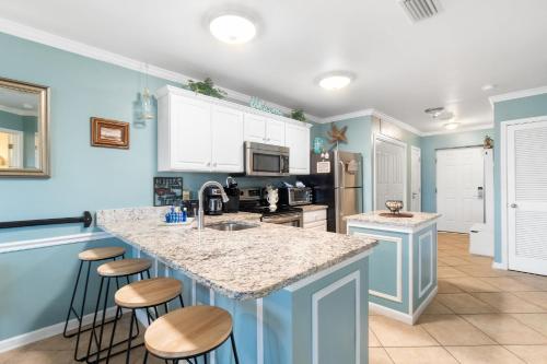 a kitchen with blue walls and a island with bar stools at Grand Caribbean 115 by Vacation Homes Collection in Orange Beach